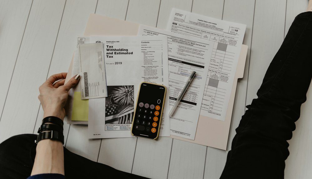 Formulários impressos, calculadora e caneta sobre uma mesa de trabalho